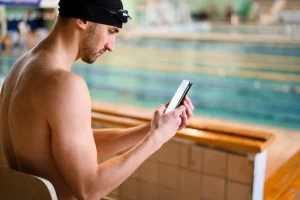Tall male swimmer using phone